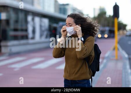 Kaukasische Frau, die eine Schutzmaske auf den Straßen aufsetzt Stockfoto