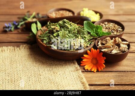 Kräuterauswahl in Kräutermedizin in Schalen auf Holztisch verwendet Stockfoto