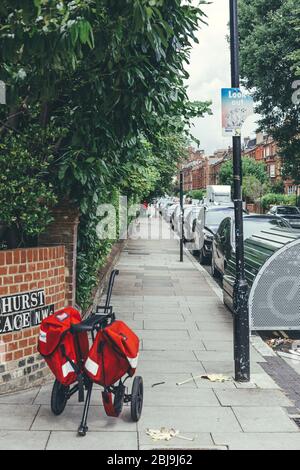 London/UK-30/07/18: Der Buggy des Postboten Royal Mail mit zwei roten Kuriertaschen. Postbote ist ein Angestellter eines Postdienstes, der Post und Parce liefert Stockfoto
