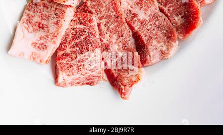 Nahaufnahme von Premium Rare Dry-Aged Rindfleisch mit marmorierter Textur mariniert mit Pfeffer und Salz auf weißem Teller serviert für Yakiniku. Stockfoto