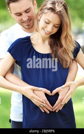 Glückliche Familie erwartet Baby auf grünen Natur Hintergrund Stockfoto