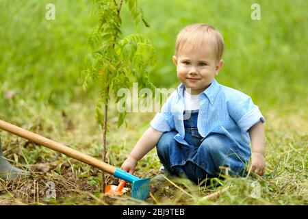 Niedlichen Baby, der Baum im Garten pflanzt Stockfoto