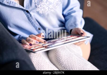 Auswählen von Filmen oder Serien im Online-Stream- und Video-on-Demand-Dienst (VOD). Frau, die ein Tablet auf der Couch verwendet. Media Streaming und Entertainment-Schnittstelle. Stockfoto