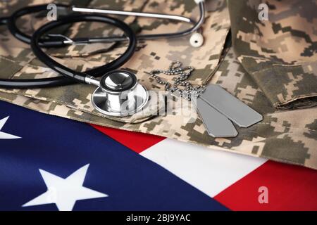 Stethoskop und Armee Token auf amerikanischer Flagge und Khaki Hintergrund Stockfoto