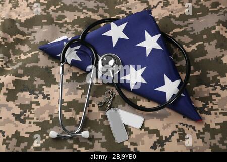 Stethoskop und Armee Token auf amerikanischer Flagge und Khaki Hintergrund Stockfoto