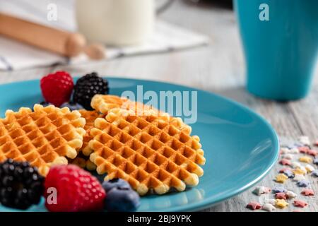 Traditionelle belgische Waffeln mit frischem Obst und Milch. Rustikaler Küchentisch. Stockfoto