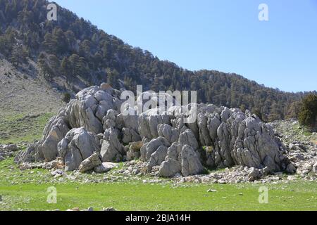 Landschaft mit Felsen auf grüner Bergwiese. Likya Yolu berühmte Touristen Patway in der Türkei. Sonniger Tag in den Bergen Stockfoto