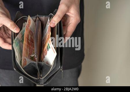 Ein Mann mit einer schwarzen Brieftasche voller russisches Geld. In einer schwarzen Brieftasche, Banknoten sind meist 5,000 Rubel pro Stück. Gehalt und Rente erhöht, Leistungen Stockfoto