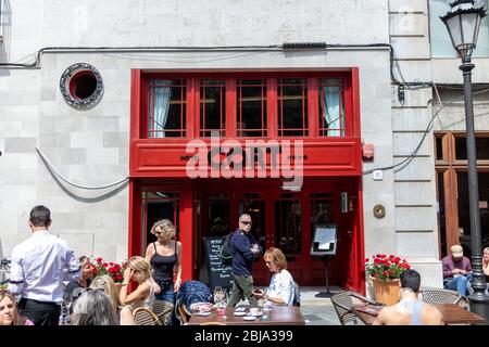 Palma, Mallorca - 10. April 2019: Touristen und Einheimische sitzen vor dem Eingang des Hotels cort in der Mitte von palma, Mallorca. Stockfoto