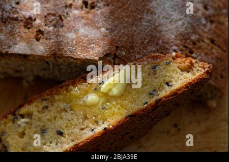 Gebutterte und verzehrfertige Brotscheiben, die gerade aus dem Ofen gekommen sind, wirken mit ihrer schmelzenden Butter köstlich Stockfoto