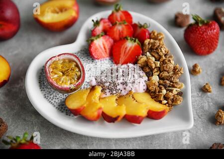 Gesundes Frühstück mit Früchten und Chia-Samen in herzförmiger Platte Stockfoto