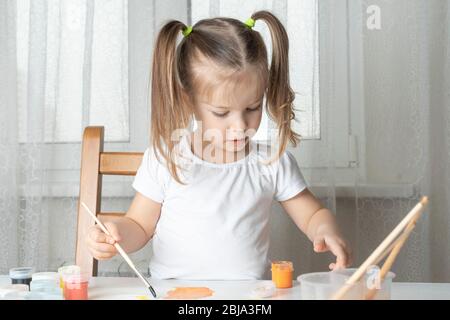 Was für ein Kind zu tun ist während der Zeit der Quarantäne und Selbstisolation spielt und malt ein Mädchen mit Öl Stockfoto