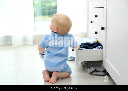 Baby wirft Kleidung aus Holzkiste Stockfoto