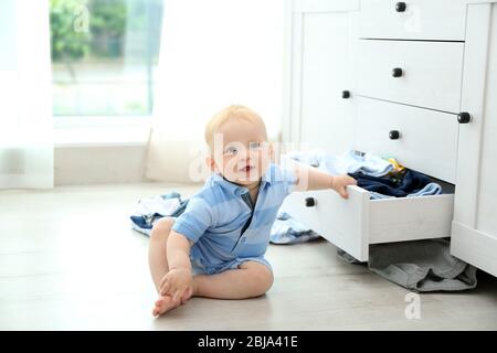 Baby wirft Kleidung aus Holzkiste Stockfoto