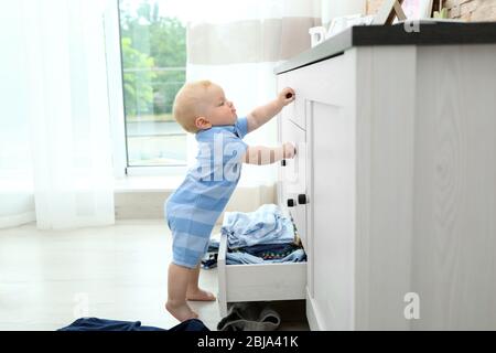 Baby wirft Kleidung aus Holzkiste Stockfoto