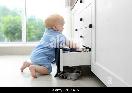 Baby wirft Kleidung aus Holzkiste Stockfoto