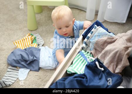 Baby wirft Kleidung aus Holzkiste Stockfoto