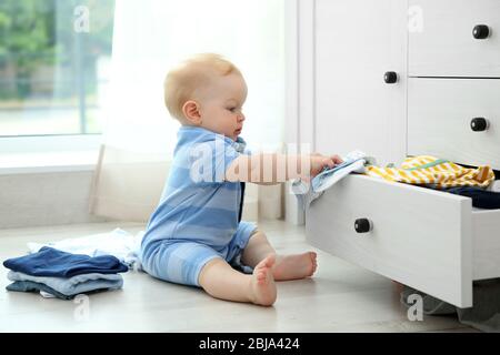 Baby wirft Kleidung aus Holzkiste Stockfoto