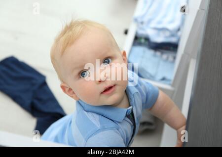 Baby wirft Kleidung aus Holzkiste Stockfoto