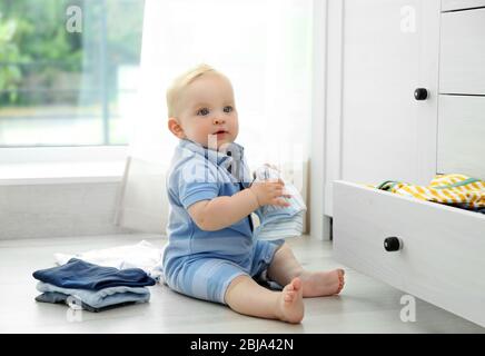 Baby wirft Kleidung aus Holzkiste Stockfoto