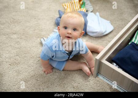 Baby wirft Kleidung aus Holzkiste Stockfoto