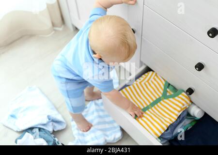 Baby wirft Kleidung aus Holzkiste Stockfoto