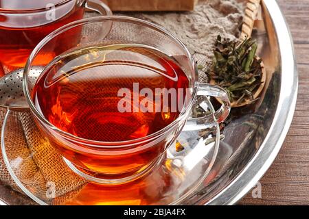 Glas Tasse Tee in silbernem Tablett auf Holztisch Stockfoto