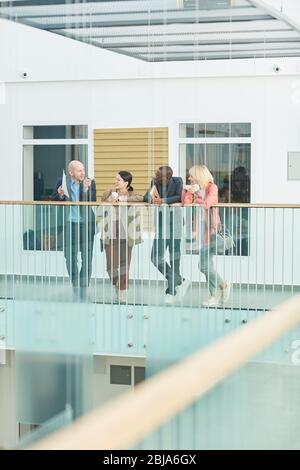 Gruppe von Geschäftsleuten, die Geschäftspläne vor einem Geschäftstreffen im Bürokorridor besprechen Stockfoto