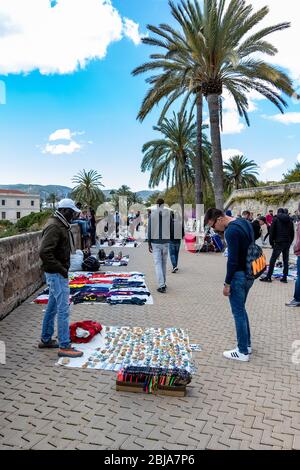 Palma, Mallorca - 10. April 2019: Afrikanische Straßenhändler versuchen, Piraterie auf Touristen in der Nähe der Kathedrale de Palama zu verstauen. Stockfoto