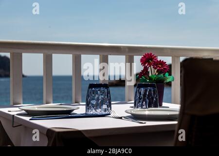 Tisch mit Stühlen und Tellern in einem Restaurant mit Blick auf das mittelmeer in sant Ulm, mallorca, spanien. Stockfoto