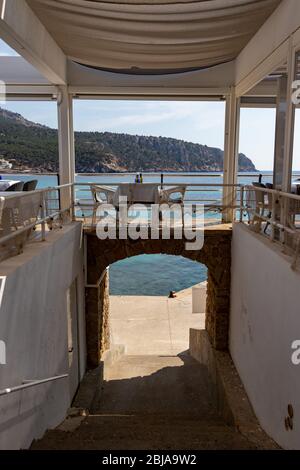 Tisch mit Stühlen und Tellern in einem Restaurant mit Blick auf das mittelmeer in sant Ulm, mallorca, spanien. Stockfoto