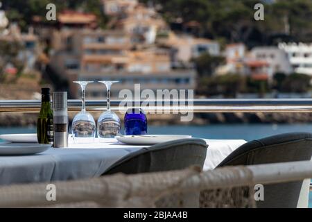 Tisch mit Stühlen und Tellern in einem Restaurant mit Blick auf das mittelmeer in sant Ulm, mallorca, spanien. Stockfoto