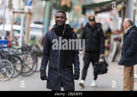 Junger schwarzer Mann mit Ohrhörer auf dem Bürgersteig Stockfoto