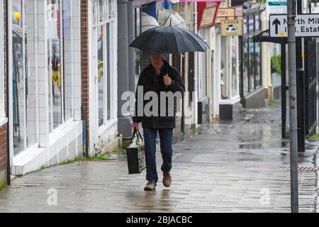 Bridport, Dorset, Großbritannien. April 2020. Wetter in Großbritannien. Ein Shopper mit Regenschirm, der sich an einem nassen Morgen in Bridport in Dorset vor dem Regen schützt. Bild: Graham Hunt/Alamy Live News Stockfoto