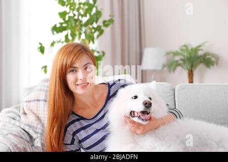 Mädchen mit Spaß mit Samoyed Hund zu Hause Stockfoto