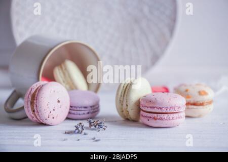 Leckere Makronen und Becher auf hellem Holztisch Stockfoto