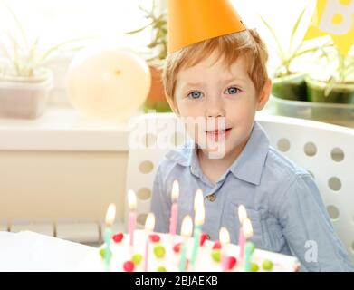 Schöner kaukasischer Junge. Geburtstagskuchen mit bunten Kerzen Stockfoto