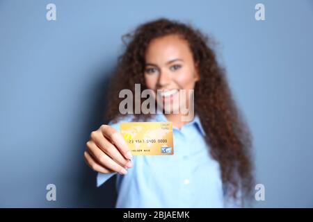 Attraktive Frau mit Kreditkarte auf blauem Hintergrund Stockfoto