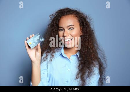 Attraktive Frau mit Kreditkarte auf blauem Hintergrund Stockfoto