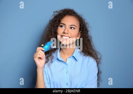 Attraktive Frau mit Kreditkarte auf blauem Hintergrund Stockfoto