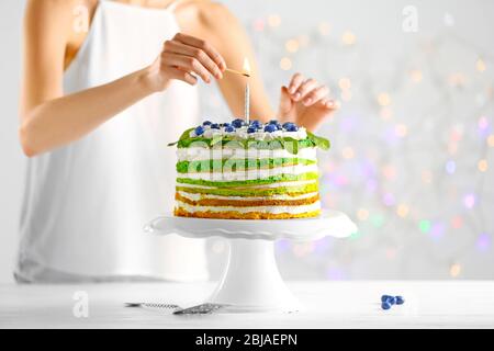 Frau Dekoration leckeren Kuchen auf hellem Hintergrund Stockfoto