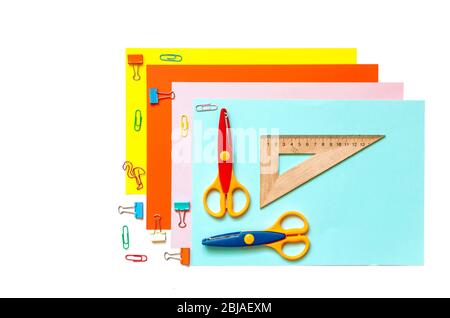 Blätter aus farbigem Papier, in einer Reihe angeordnet, Buntstifte, Scheren und Vorräte auf einem weißen Tisch. Kinderkunst, Handwerk für Kinder oder die Vorbereitung eines Kindes für sc Stockfoto