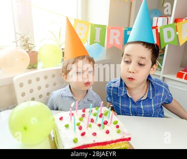 Kinder feiern Geburtstag und blasen Kerzen auf hausgemachten Kuchen Stockfoto