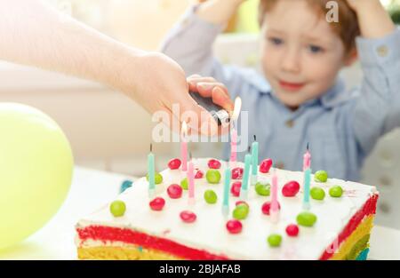 Kleiner Junge feiert Geburtstag. Kind bläst Kerzen auf Kuchen aus Stockfoto