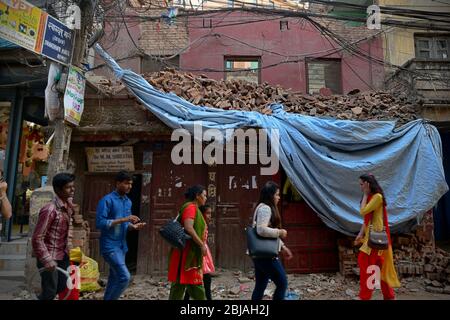 Ein Jahr nach den Erdbeben von 2015 gehen Bürger von Kathmandu vor einem Gebäude mit Trümmern in der Gegend von Thamel, Kathmandu, Nepal. Stockfoto