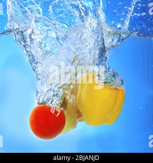 Gruppe von frischem Obst und Gemüse, die in Wasser auf blauem Hintergrund fallen Stockfoto