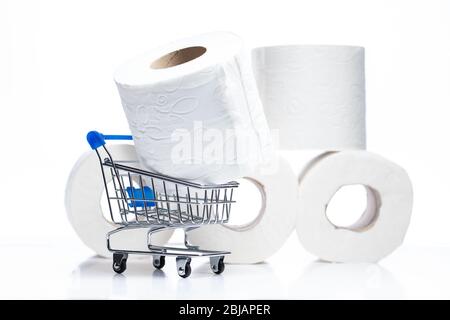 Lebensmitteleinkaufwagen mit Toilettenpapierrollen dahinter. Konzept des Mangels an Toilettenpapier in den Geschäften aufgrund Coronavirus, Covid-19 Stockfoto