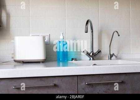 Ein Fragment der Küche. Arbeitsplatte aus Kunststein mit integriertem Waschbecken. Zwei Wasserhähne. Eine für gefiltertes Wasser. Flüssigseife zum Waschen von Händen und di Stockfoto