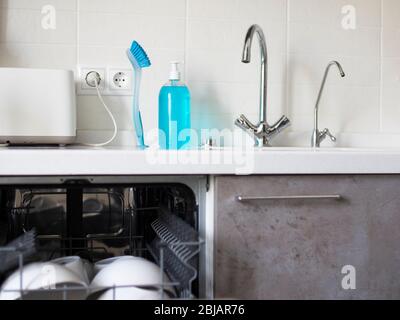 Ein Fragment der Küche. Arbeitsplatte aus Kunststein mit integriertem Waschbecken. Zwei Wasserhähne. Eine für gefiltertes Wasser. Flüssigseife zum Waschen von Händen und di Stockfoto