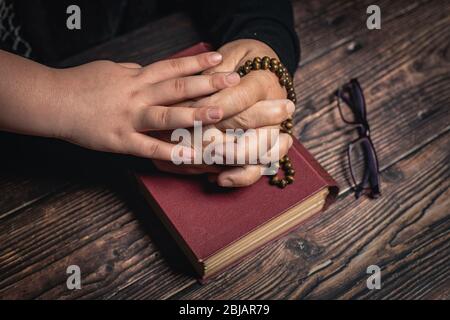 Mädchen und Alte Frau mit geschlossenen Händen halten Rosenkranz auf heiligen Buch zu Hause bleiben und für den Schutz beten ageainst coronavirus covid-19 pandemi conc Stockfoto